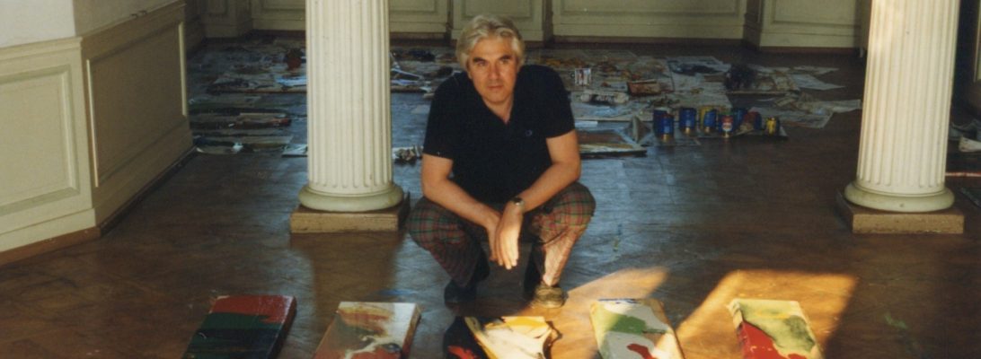 Franz E. Schilke im Atelier zwischen Säulen, um ihn herum Leinwände auf dem Boden